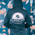 Rear view of a person wearing a Flagstaff Liquor Mountain Logo full zip hoodie with mountain emblem against floral background.